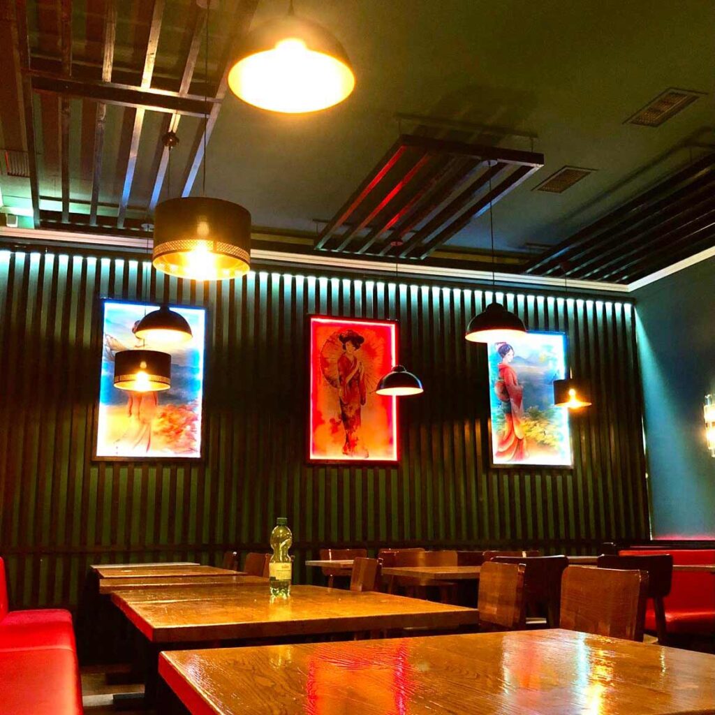 Ein gemütliches Restaurant mit rot gepolsterten Sitzbänken und bunter Kunst an den Wänden.