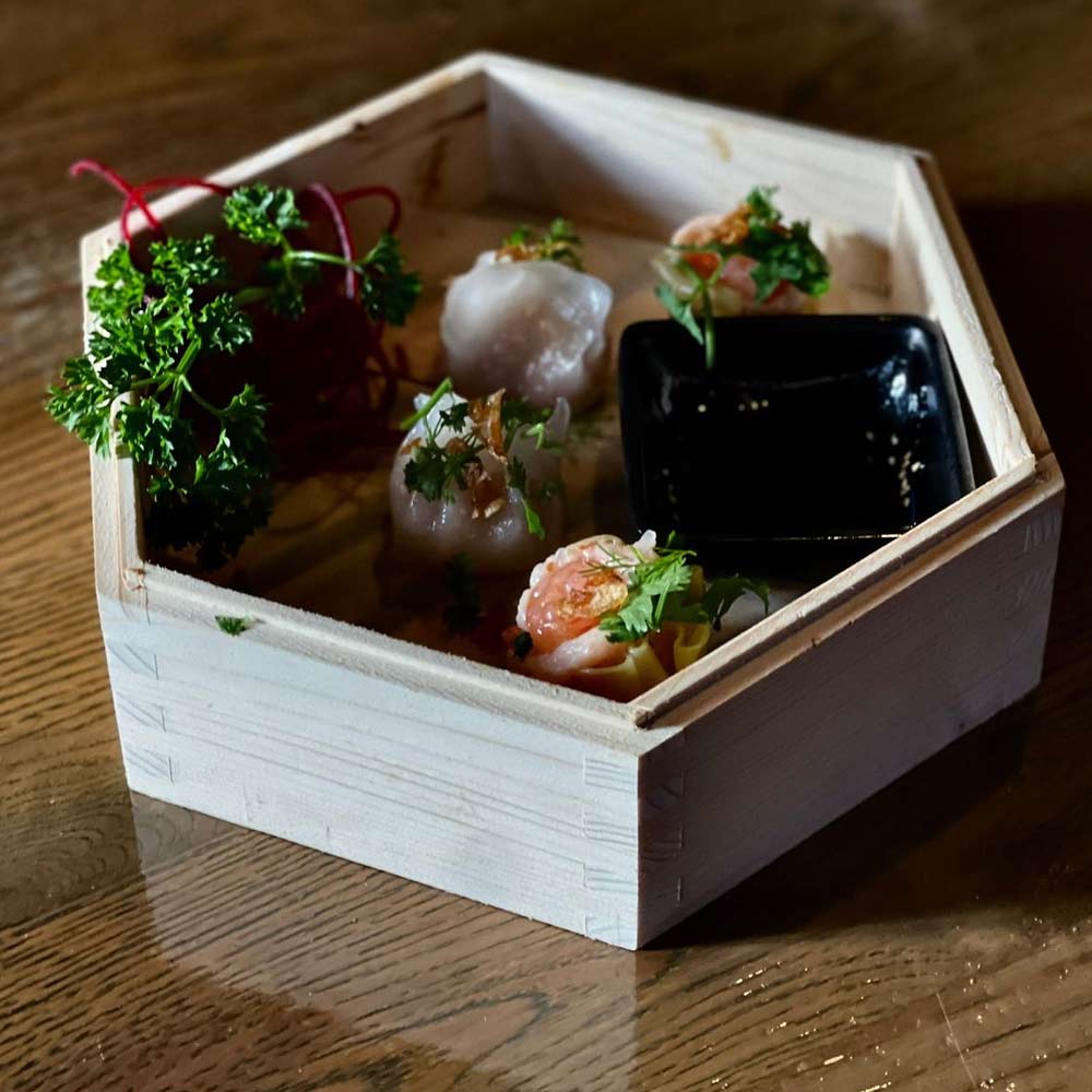 Holztablett mit sechs Sushi-Rollen, garniert mit grünem Koriander.