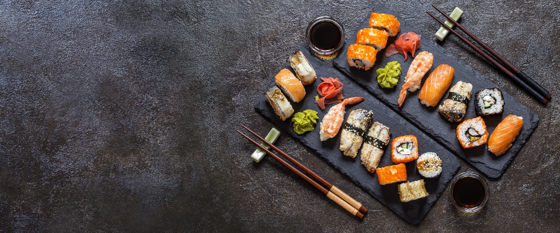 Sushi-Rollen mit Reis und Fisch, Sojasauce auf dunklem Hintergrund