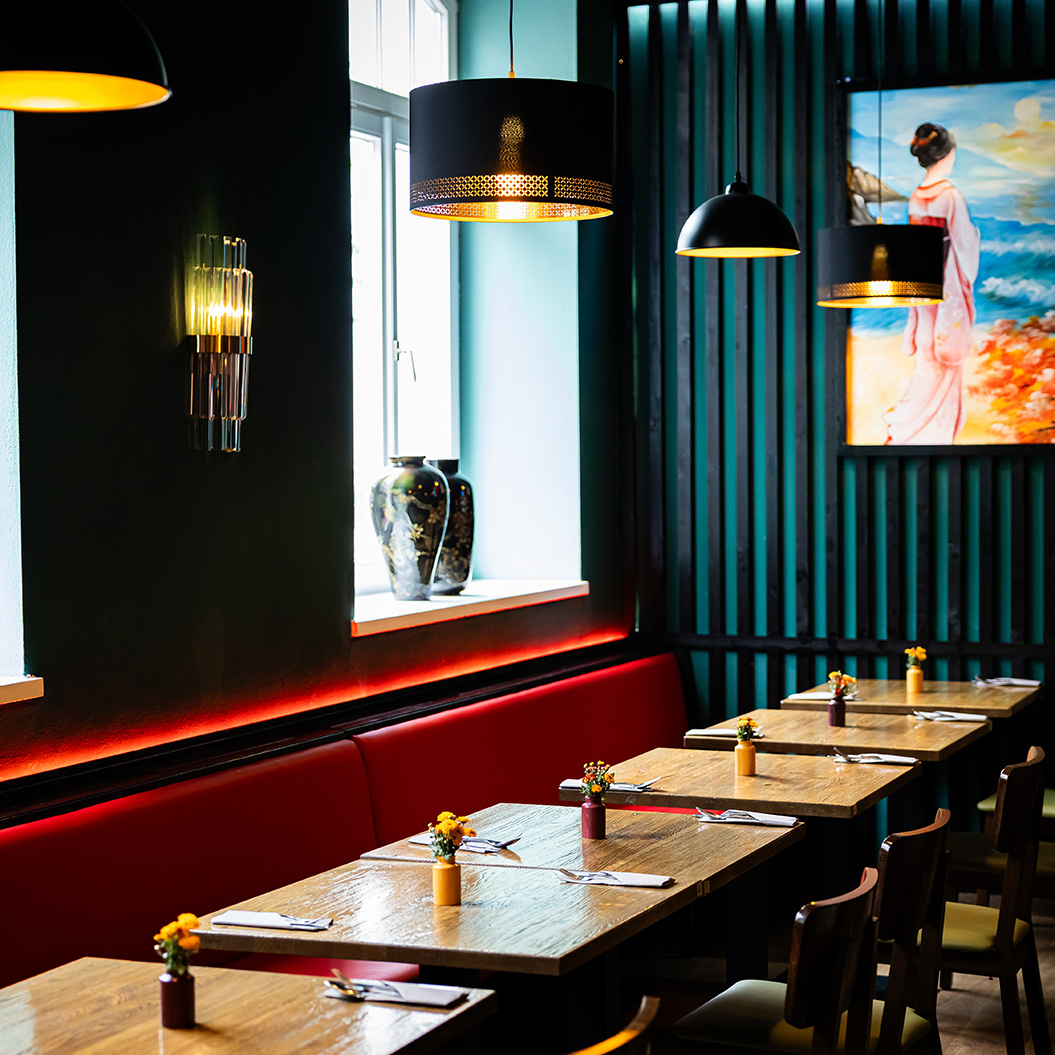 Ein stilvolles Restaurant mit gedeckten Holztischen, roten Bänken und bunter Wandkunst