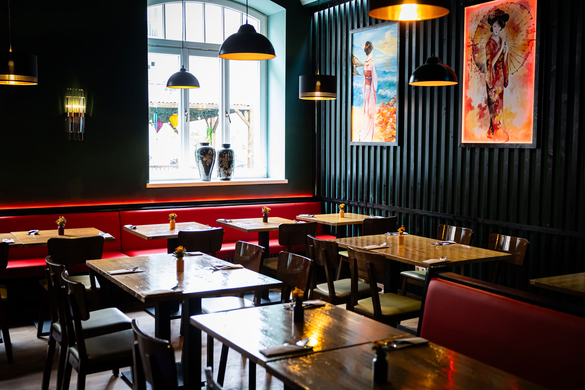 Ein modernes Restaurant mit Holztischen, roten Bänken und Kunst an den Wänden