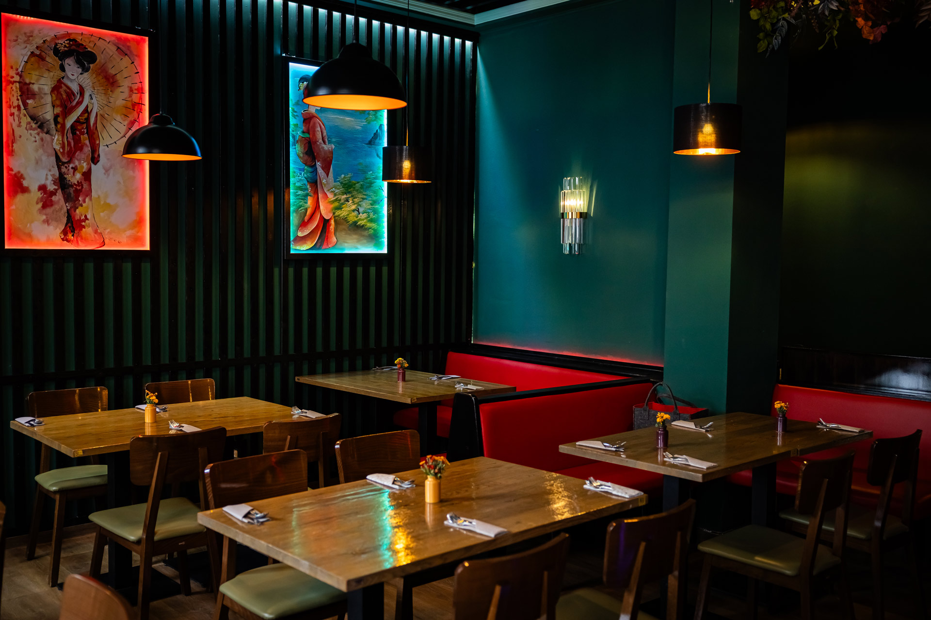 Ein modernes Restaurant mit Holztischen, roten Sitzbänken und farbenfroher Wandkunst