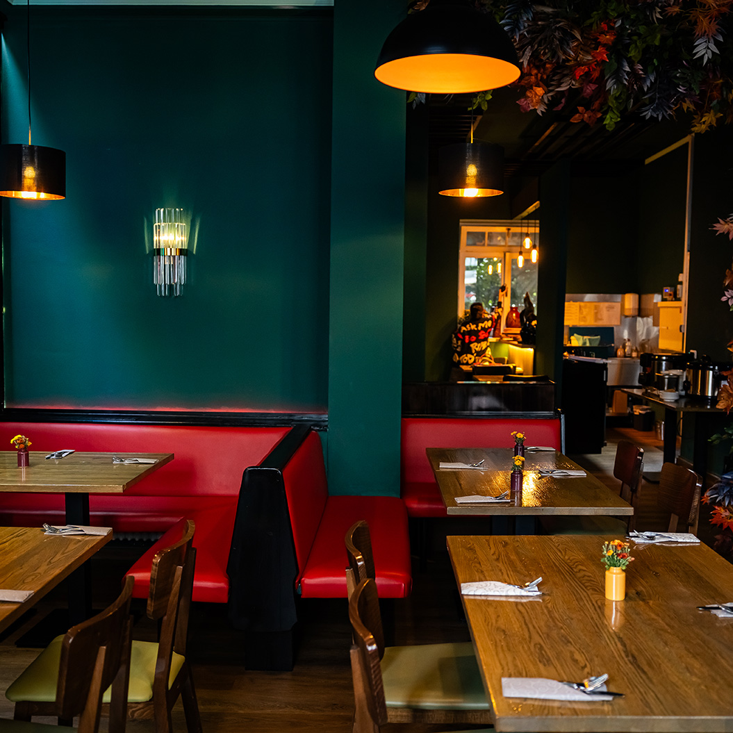 Ein gemütliches Restaurant mit rot gepolsterten Bänken und grün gestrichenen Wänden