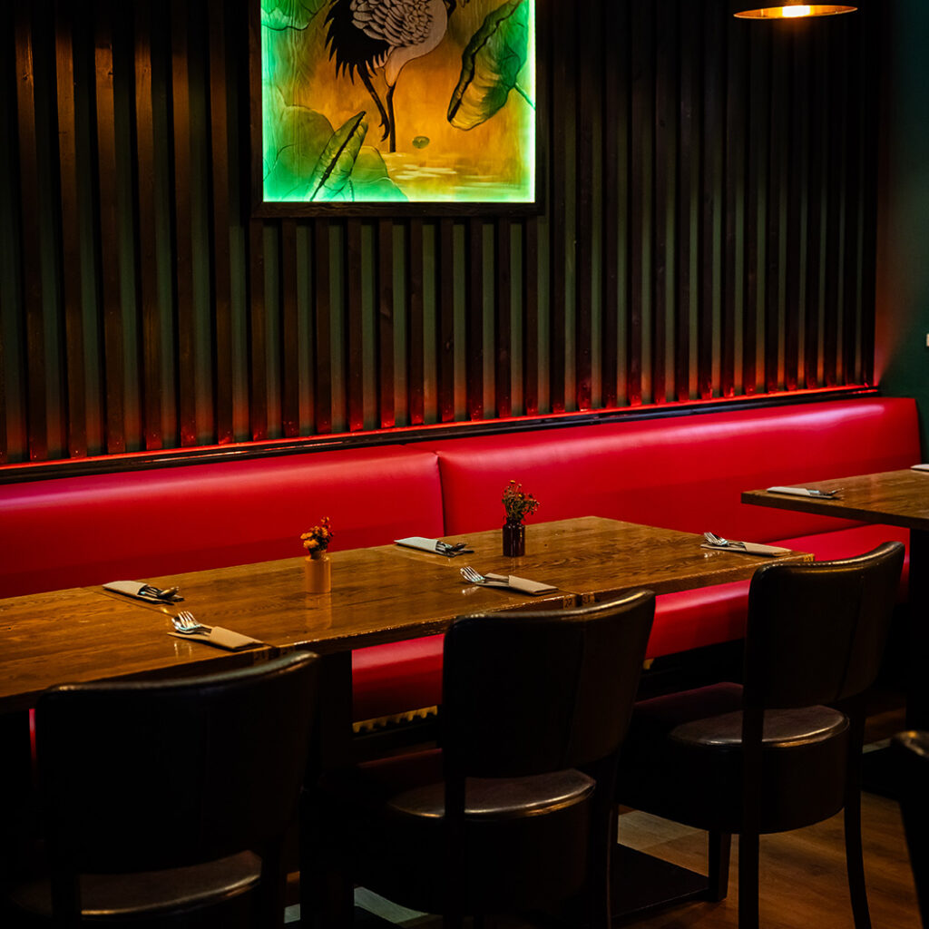 Gemütliches Restaurant mit roten Sitzbänken, Holztischen und stilvoller Beleuchtung