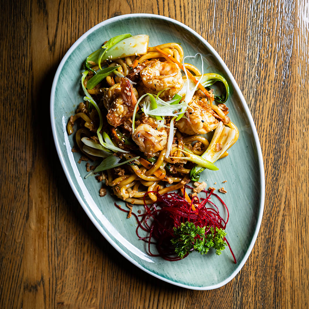 Ein asiatisches Nudelgericht mit Garnelen, Frühlingszwiebeln und buntem Gemüse